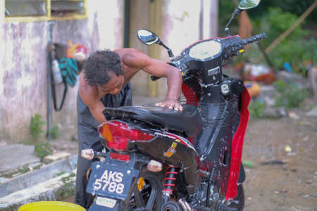 Muadzam Shah, Malaysia - June 17th, 2020 : The Orang Asli (First People) of West Malaysia cleaning and washing his motorcycleのeditorial素材