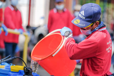 Muadzam Shah-Malaysia - June 22th, 2020 : Workers   in protective suit with gloves adding disinfectant and mixing chemicals in tank reservoir to start disinfecting against  COVID-19のeditorial素材