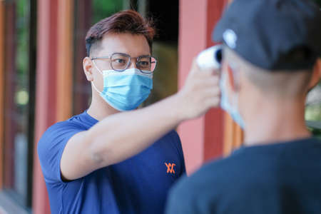 Muadzam Shah,Malaysia-June 23th, 2020: Teacher using thermometer temperature screening student for fever against the spread of COVID-19 while student coming back to school, Education concept.のeditorial素材