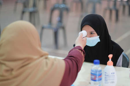 Muadzam Shah,Malaysia-June 23th, 2020: Teacher using thermometer temperature screening student for fever against the spread of COVID-19 while student coming back to school, Education concept.のeditorial素材