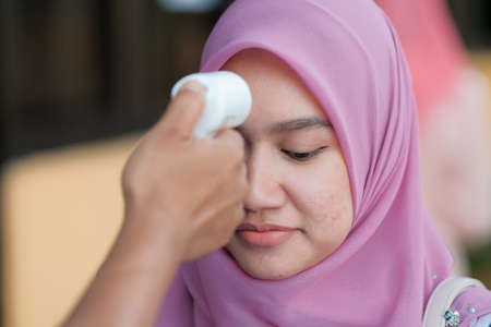 Muadzam Shah, Malaysia - July 1st, 2020: New normal, men using infrared thermometer for measuring temperature before entrance in office.People wear protective face masks, COVID-19 outbreak preventionのeditorial素材