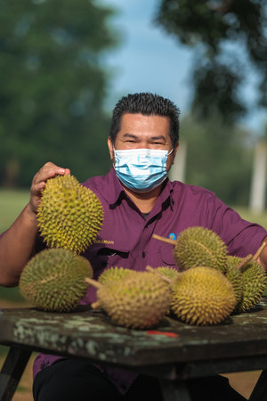 Muadzam Shah, Malaysia - July 1st ,2020:  Happy asian men enjoy posing and eating durian fruit with...