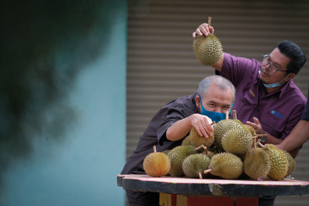 Muadzam Shah, Malaysia - July 1st ,2020:  Happy asian men enjoy posing and eating durian fruit with...