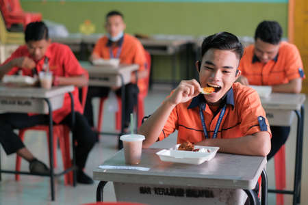 Muadzam Shah, Malaysia - June 25th, 2020 : Student  eating food in the classroom. Social distancing. Concept protection of corona virus or covid-19.のeditorial素材
