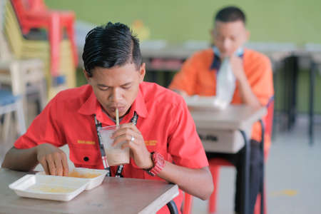 Muadzam Shah, Malaysia - June 25th, 2020 : Student  eating food in the classroom. Social distancing. Concept protection of corona virus or covid-19.のeditorial素材