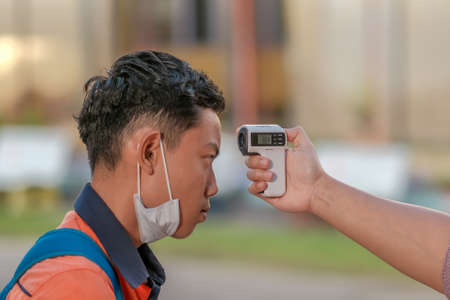 Muadzam Shah, Malaysia - July 7th, 2020 : Teacher using thermometer temperature screening student for fever against the spread of COVID-19 while student coming back to school, Education concept.のeditorial素材