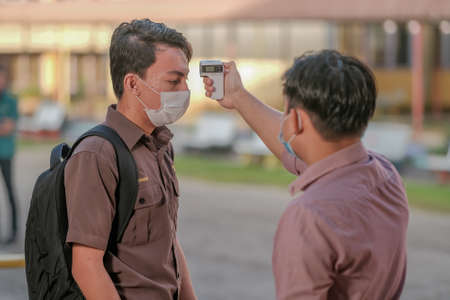Muadzam Shah, Malaysia - July 7th, 2020 : Teacher using thermometer temperature screening student for fever against the spread of COVID-19 while student coming back to school, Education concept.のeditorial素材