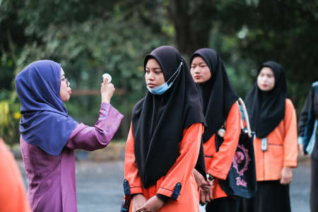 Muadzam Shah, Malaysia- July 9th, 2020:  Teacher using thermometer temperature screening student for fever against the spread of COVID-19 while student coming back to school, Education concept.のeditorial素材