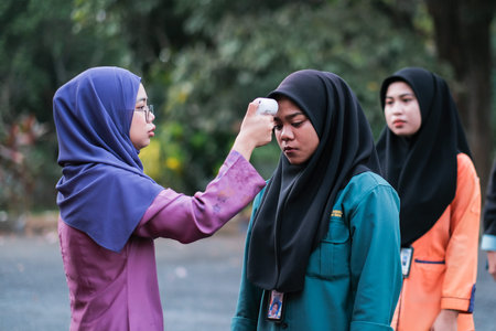 Muadzam Shah, Malaysia- July 9th, 2020:  Teacher using thermometer temperature screening student for...