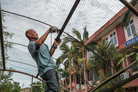 Muadzam Shah, Malaysia- July 7th, 2020: Worker using grinding machine to cut metal roof frame.のeditorial素材