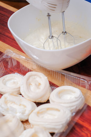 The making of mini pavlovas with whipped cream and fresh fruit in the kitchen