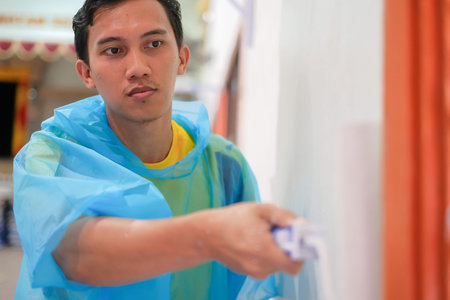 Man with disposable overalls coveralls hood painters decorator suit protective working in the hall .
