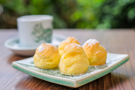 Cream puff with a cup of tea in the garden.