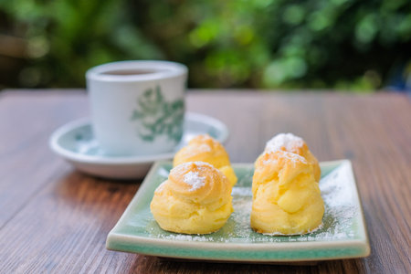 Cream puff with a cup of tea in the garden.