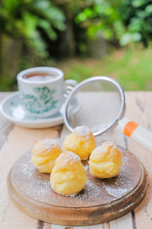 Cream puff with a cup of tea in the garden.