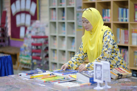 Muadzam Shah, Malaysia - August 12th, 2020 :  Cheerful mature librarian posing holding books.のeditorial素材