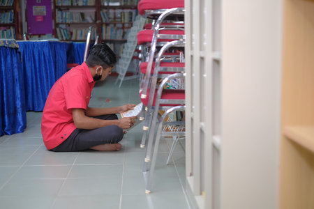 Muadzam Shah, Malaysia - August 12th, 2020 :  Male college student reading a book in the  library