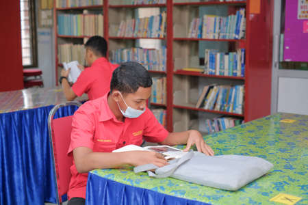 Muadzam Shah, Malaysia - August 12th, 2020 :  Male college student reading a book in the  libraryのeditorial素材