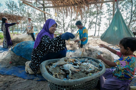 Kuala Rompin, Malaysia- August 30th,2020 : Childrens collecting and cleaning fishing nets after the fresh catch of the day.のeditorial素材