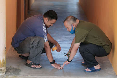Muadzam Shah, Malaysia -  June  23th, 2020 : Men making arrows and taped stripes to assure social distancing. Secure marking of lines on floor for directionsのeditorial素材
