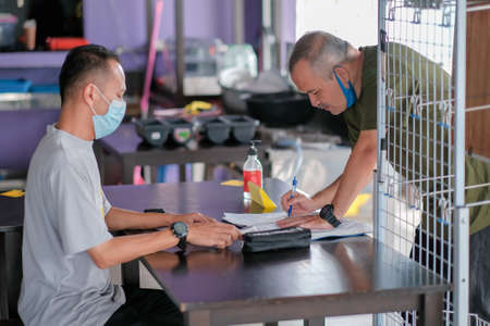 Muadzam Shah, Malaysia -  June  23th, 2020 : The Manager of a restaurant  the body temperature of the customer with a thermal imaging device.のeditorial素材