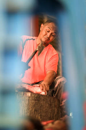 Muadzam Shah, Malaysia- August 10th,2020 : Unidentified man  carving a rack of meat with a sharp  axeのeditorial素材