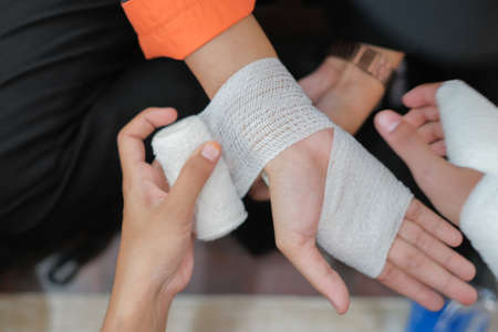 Student first aid training in the hall. Student trying to splint the hand  of a patient's broken hand incident with elastic bandage in college.のeditorial素材