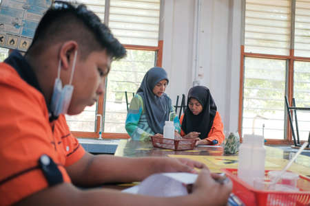 Muadzam Shah, Malaysia - October 5th, 2020 :  Teacher and college students teaching school work and explaining problem solution studying  in a table at class.Education conceptのeditorial素材