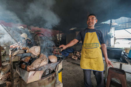 Kota Bharu, Malaysia - July 30th, 2020 : The portrait of husband and wife  making a local Malaysian desert called Akok Kedut using   coconut husks for fuel.のeditorial素材