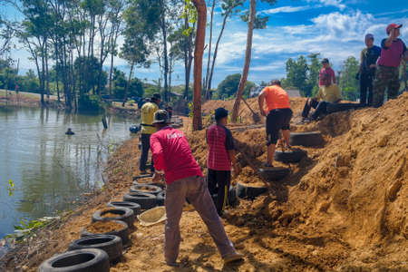 Muadzam Shah, Malaysia - October 18th,2020:   Residents helping each other in a teamwork spirit in clearing and cleaning the lakeside area . People doing landscaping works .のeditorial素材