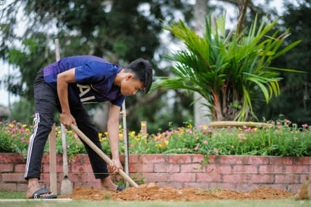 Muadzam Shah, Malaysia - October 14th,2020:  Worker digging hole for stump concrete foundation holderのeditorial素材