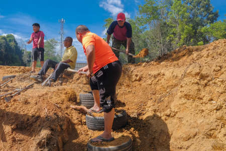 Muadzam Shah, Malaysia - October 18th,2020:   Residents helping each other in a teamwork spirit in clearing and cleaning the lakeside area . People doing landscaping works .のeditorial素材