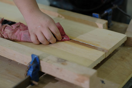 Carpenter joining pieces of wood with long bar clamp and glue