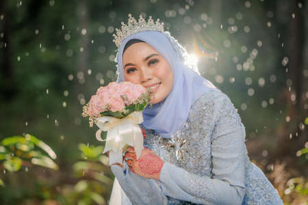 Wedding photo shooting. The bride  wearing baby blue  Malay traditional cloth at the forest.の写真素材