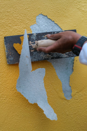 Removing paint with stainless steel plastering trowelの写真素材
