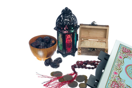 Islamic concept - The Holy Al Quran, dates , lantern, rice,coins  and prayer beads with written Arabic calligraphy meaning of Al Quran, Arabic word translation : The Holy Al Quran (holy book of Muslim), on white background.の写真素材