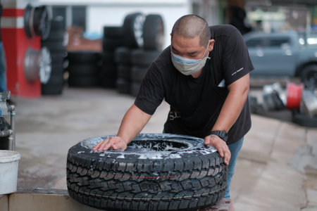 Kuala Lumpur , Malaysia - June 29th, 2020 : Tyre change on the car in a workshop by a mechanic.のeditorial素材
