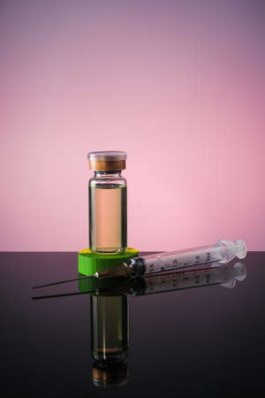 A Vaccine in vial and syringe close-up on a  glass table, medical concept, laboratory, subcutaneous injection vaccination, dose. Disease treatment immunization.の写真素材