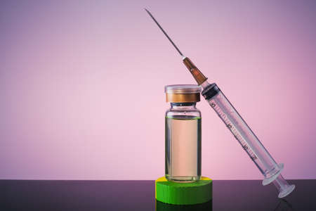A Vaccine in vial and syringe close-up on a  glass table, medical concept, laboratory, subcutaneous injection vaccination, dose. Disease treatment immunization.の写真素材