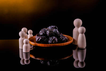 Ramadan Kareem Festival, Dates at wooden bowl with wooden firgures standing on black backgroundの写真素材