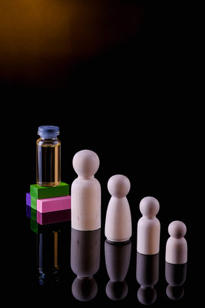 Vaccine and people wooden figures on black  background. Vaccination concept.