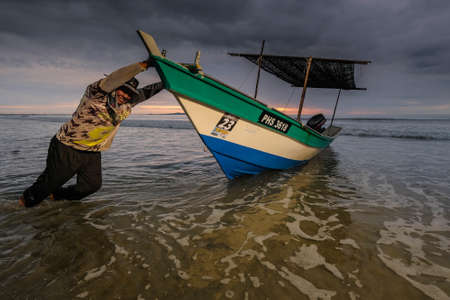 Beserah, Malaysia - April 24th, 2021 : Fisherman pushing their boat, going fishing in the early morning in Beserah. Selective focus.のeditorial素材