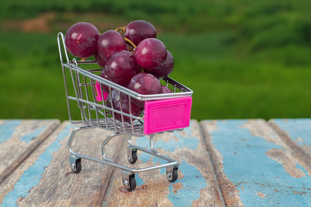 Fresh red grape fruit in wooden on rustic wood table background.