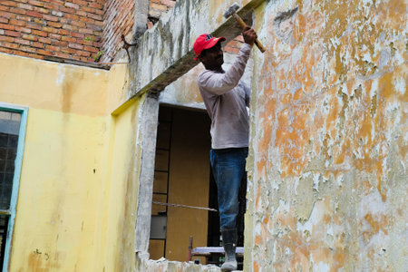 Demolition work and rearrangement. worker with sledgehammer destroying wallのeditorial素材