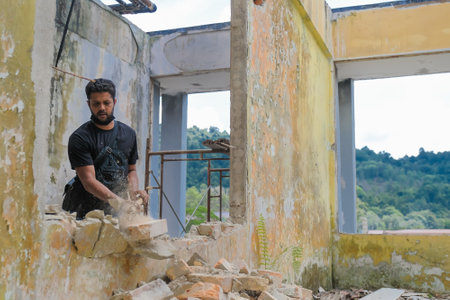 Demolition work and rearrangement. worker with sledgehammer destroying wallのeditorial素材