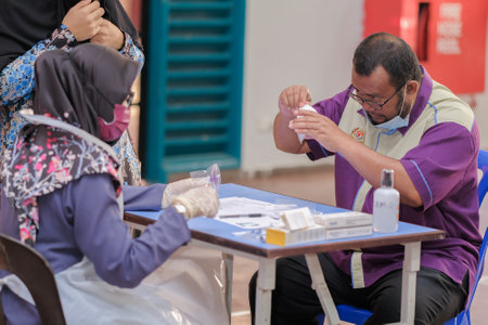 Muadzam Shah, Malaysia - January 25th, 2022 : Teacher make Covid-19 rapid test with saliva sample in the hall.のeditorial素材