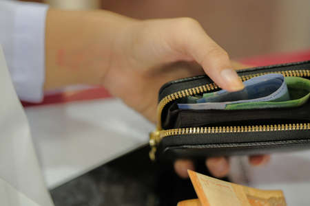 Woman putting money in a wallet. Close-up. Selective focus.の写真素材