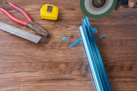 Worker using grinding machine to cut steel roof batten.の写真素材