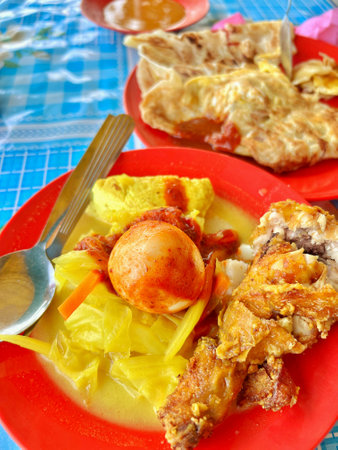 Fried chicken with curry and vegetables in red plate on blue tableclothの写真素材