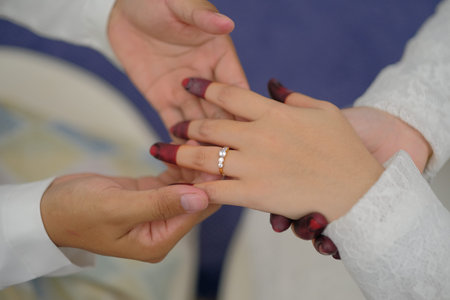 Hands of the bride and groom on a wedding day. The bride wears a wedding ring